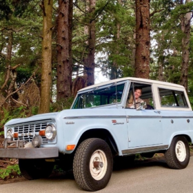 Kerry Moller taking a Ford Bronco for a drive through a forest.